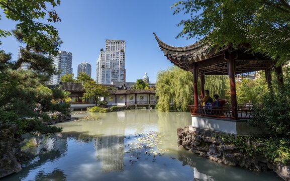 Garden with pond, Traditional Chinese Pagoda in the Dr. Sun Yat-Sen Classical Chinese Garden, high-rise buildings in the back, Vancouver, British Columbia, Canada