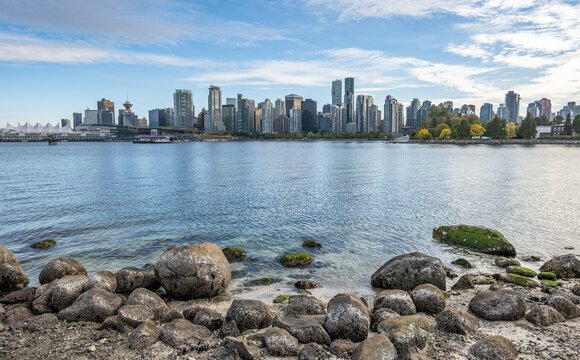 Stones on the coast, view across the sea from Hallelujah Point to skyline with skyscrapers, Stanley Park, Vancouver, British Columbia, Canada