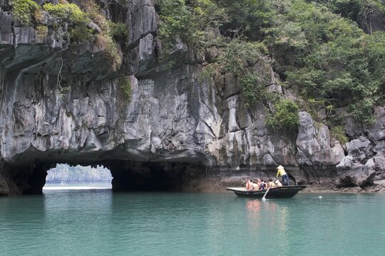 Rowing boat at the rock tunnel in Halong Bay, Gulf of Tonkin, Vietnam