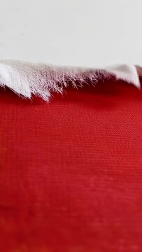 Vertical video: Zooming camera along torn white sheet in studio, showing frayed edge and red cloth