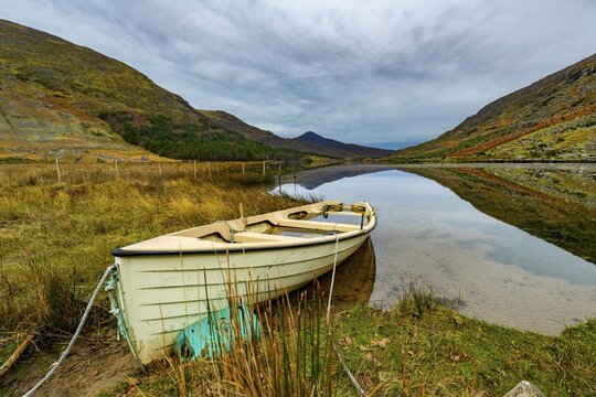 Small mountain lake with reflection and rowing boat in autumn landscape, Killarny, County Kerry, Ireland