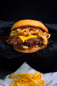 Gourmet bacon smash burger with crispy onions served on black background for menu design