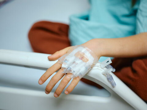 Boy lying in a hospital bed with an IV line attached to his hand.