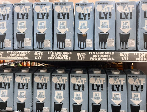 Bali, Indonesia - March, 5, 2026: A display of Oatly oat milk cartons is neatly arranged on a supermarket shelf. The cartons are primarily blue with black graphics.