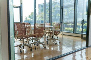 Modern conference room with glass walls and city view, empty chairs around a table © FotoArtist