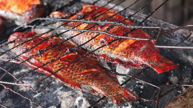 Traditional grilling fish over charcoal fire outdoor cooking