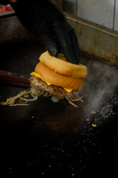 Hot burger buns being toasted on a steaming commercial griddle in a professional restaurant kitchen