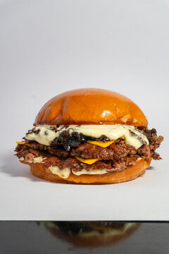 Double smash burger with molten white cheese and caramelized onions on soft brioche bun isolated on white