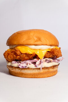 Gourmet fried chicken burger with melted cheddar cheese and fresh coleslaw salad on a toasted brioche bun