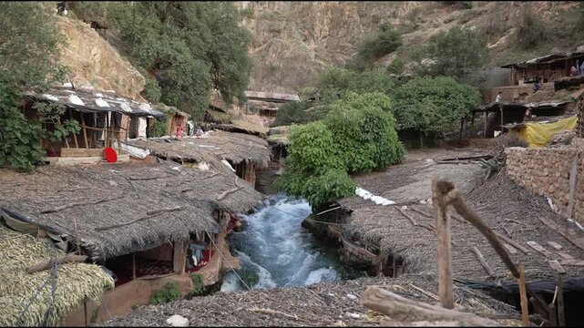 Scenic view of traditional rustic cafes with thatched roofs built over the fast-flowing Oum Er-Rbia river springs in the Middle Atlas mountains, Morocco.