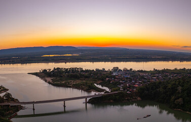 Fototapeta premium Drone perspective of Pak Kading at dusk, where warm orange and pink skies illuminate the river landscape and rural surroundings of Bolikhamxay Province.