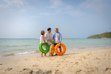 Multigenerational Asian family enjoying summer beach vacation, playing and relaxing together.