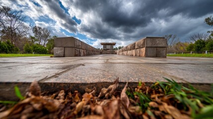 Obraz premium Memorial Pathway Under Dark Stormy Clouds with Windswept Leaves