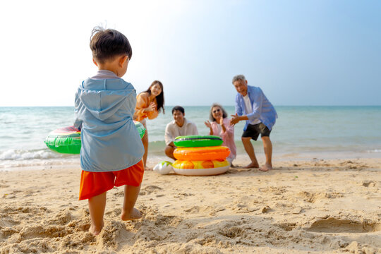Multigenerational Asian family enjoying summer beach vacation, playing and relaxing together.