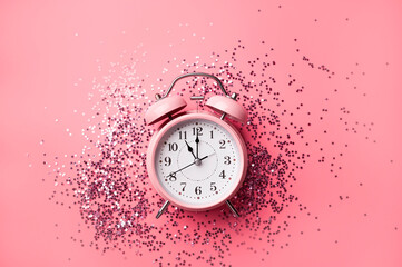Trendy pink alarm clock with confetti stars on pink background. Time to sleep, concept of health and circadian rhythms, insomnia. Women's beauty routine, delicate blog background. Flat lay top view