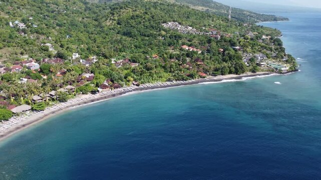 Aerial drone orbiting left revealing panoramic coastline and hillside scenery in Amed, Bali, Indonesia.