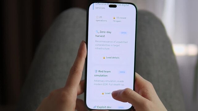 Hands holding mobile phone with cybersecurity dashboard, reviewing red team simulation and exploit development services. Innovative IT security, network protection and risk management concept ideal