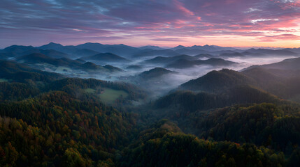 Misty mountain landscape with dense forest and colorful sky at sunrise, creating peaceful and serene atmosphere in nature