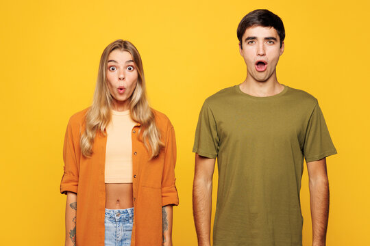 Young shocked surprised amazed couple two friends family man woman wear casual clothes looking camera with opened mouth together isolated on pastel plain light yellow color background studio portrait.