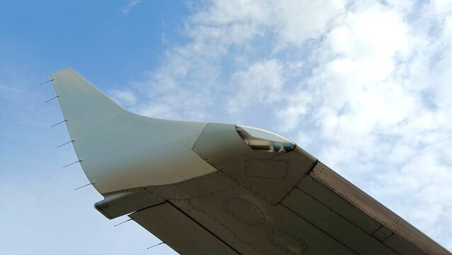 Aircraft wing tip and aerodynamic winglet against a blue sky with soft clouds, highlighting aviation engineering details and modern aircraft design
