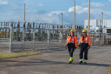Engineers working on site in electricity substation. Technician wearing safety helmets inspecting in electricity substation at a wind turbine farm.