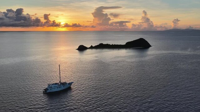 A serene sunrise silhouettes a small island in the Vatu-i-ra seascape in Fiji. This area is a marine protected area known for its high biodiversity and is a destination for divers and snorkelers.