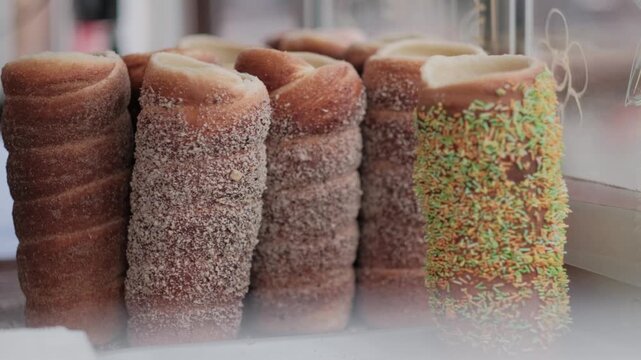 Traditional Hungarian chimney cakes coated in sugar and cinnamon displayed at an outdoor street food market