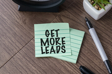 GET MORE LEADS text written on green sticky notes on a wooden desk, representing marketing strategy, customer acquisition, and sales funnel growth.