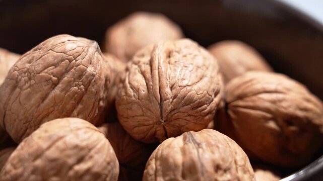Whole walnuts in shell filling ceramic bowl. Natural texture and organic food. Agriculture harvest concept