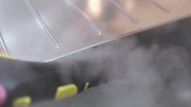Close up of a steam cleaner nozzle sanitizing a stainless steel kitchen sink with hot vapor