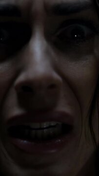 Vertical video: Showing adult woman shocked, angry after offscreen cue in dim closeup, baring teeth