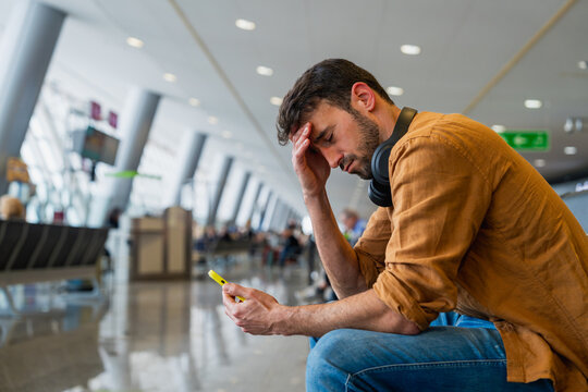 Stressed male traveler experiencing travel delay in airport