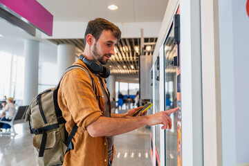 Male traveler making purchase at airport vending machine © Martí Rosselló