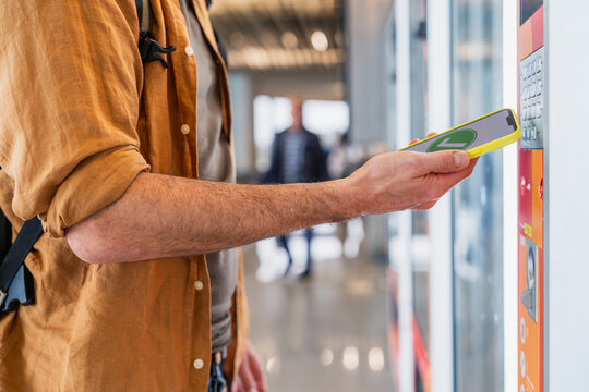 Traveler paying with smartphone at vending machine in airport