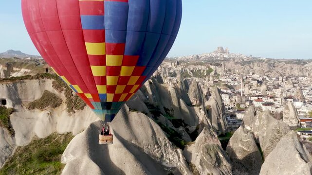 Colourful Red Blue Yellow Colours Hot Air Baloons Aerial Drone Flight. The great tourist attraction of Cappadocia. Cappadocia landscape with rocks and houses. Goreme, Cappadocia, Turkey.