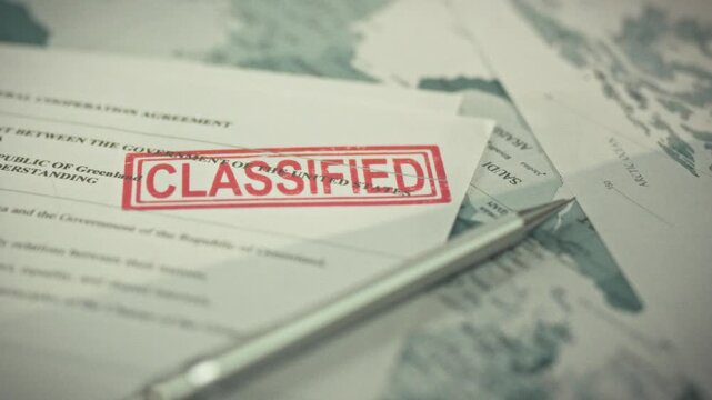 A confidential intergovernmental document with a large red secret stamp is processed according to strict access protocol. The classified documents lie on a paper map of the world on the table