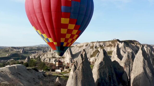 Colourful Red Blue Yellow Colours Hot Air Baloons Aerial Drone Flight. The great tourist attraction of Cappadocia. Cappadocia landscape with rocks and houses. Goreme, Cappadocia, Turkey.