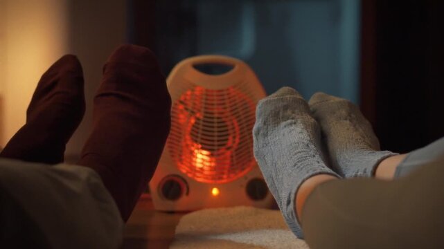 A couple snuggles on the floor in warm winter socks, basking in the cozy warmth emitted by the heater on a relaxing evening at home, prioritizing comfort and relaxation