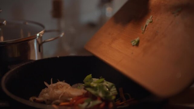 A skilled chef delicately adds aromatic basil leaves to sizzling vegetables in a hot pan, amplifying flavor through precise fry cooking techniques in a bustling kitchen