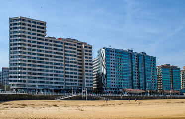 High rise residential buildings located Avenida Castilla and El Muro in Gijón, Spain. The buildings feature distinct modern architectural styles of glass and cement. Urban living with sea views.
