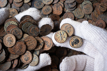 Hands in white gloves holding ancient coins of Roman empire. Numismatic collection of old bronze money. Archaeology and historical preservation concept © scaliger