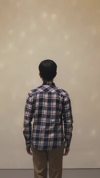 Vertical video: Standing man in plaid top, khakis seeing lights forming as soft dots on studio wall
