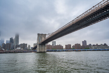 Fototapeta premium Brooklyn Bridge perspective from boat with Manhattan skyline background