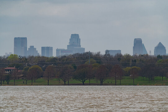 Skyscrapers and buildings making up parto the the Dallas, Texas skyline rising boe the trees on the shore of White Rock Lake.