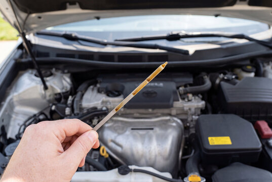 Hand holding dipstick to check oil level in car engine
