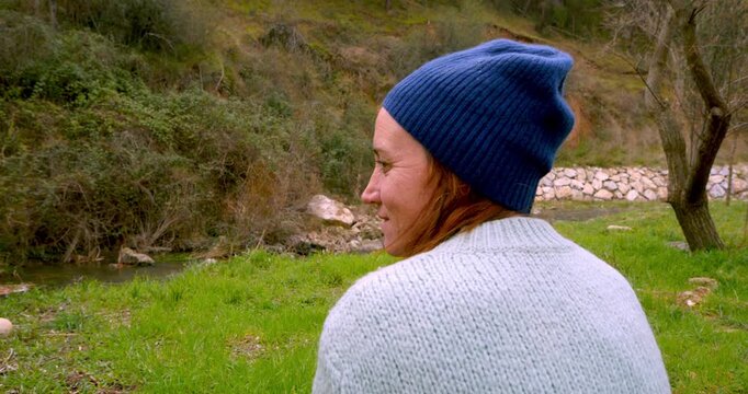 Quiet Contemplation in Nature: A person, wrapped in a knitted cap and sweater, finds solace in the tranquil embrace of the natural world, their gaze reflecting the serenity of the outdoor.