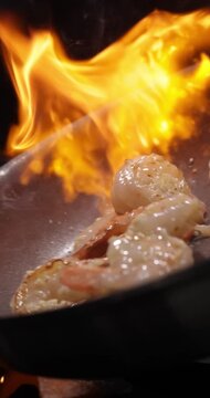 Slow-motion vertical video shot of shrimp stir-fry  in a wok with fire