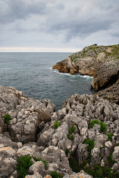 Rocky cliffs above the ocean with open sea and overcast skies