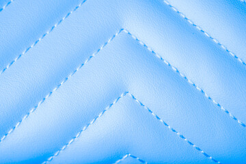 Fototapeta premium Close up of smooth vibrant light blue quilted material showcasing a delicate zigzag stitch pattern