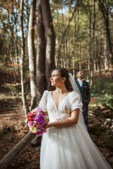 Naklejka premium Portrait of bride and an groom in nature, surrounded by a forest.